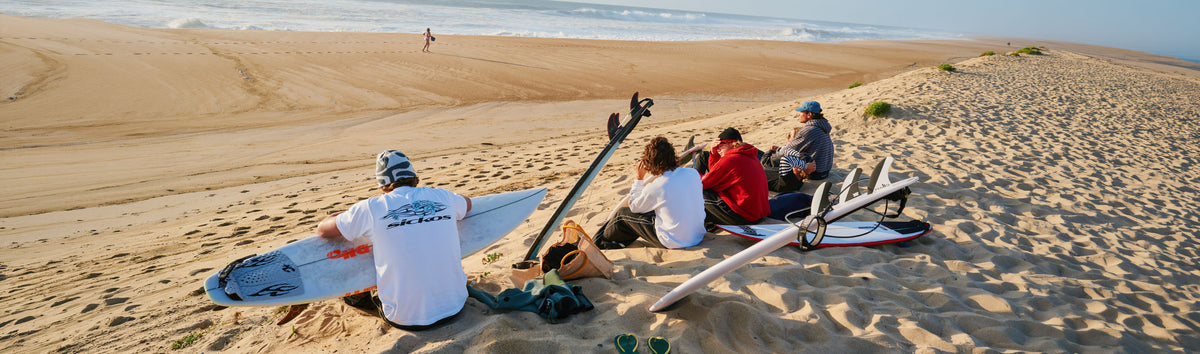 The Sickos crew with surfboards on the beach